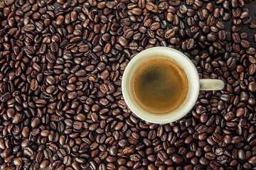 Top-view shot of a cup of hot coffee on coffee bean background