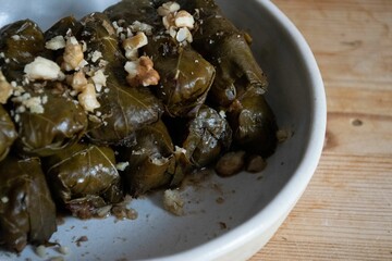Dolma sprinkled with chopped walnuts in a white ceramic bowl