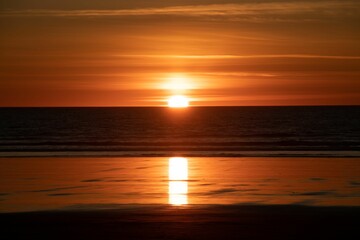 Stunning seascape of a beach at sunset, showing a beautiful orange sky illuminated by the  sun