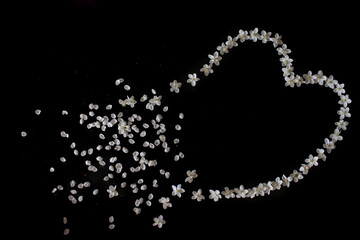 A broken heart made of cherry blossoms on a black table