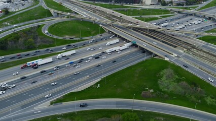 Aerial view over highway expanse, commuter cars threading through city's vascular roadways. Drone...