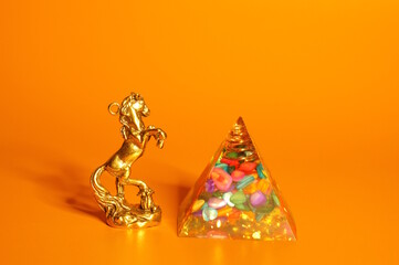 A statuette of a metal horse and a glass pyramid with stones inside. Finance and economics.