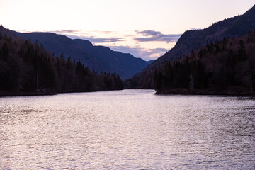 Sunset view of large river flowing in a valley between mountains in the Jacques-Cartier National Park, Stoneham-et-Tewksbury, Québec, Canada