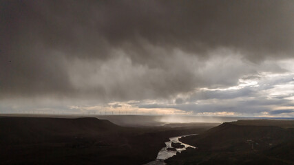Obraz premium Dramatic contrast photo with massive rain clouds and windmills in the background. Drone photo