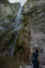 Waterfall hidden inside the forest, beauties of Slovenia to be discovered. Near Nova Gorica, Tolmin village. Water spray and vivid rainbow forms from the waterfall that falls sheer onto the rock.