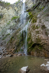 Waterfall hidden inside the forest, beauties of Slovenia to be discovered. Near Nova Gorica, Tolmin village. Water spray and vivid rainbow forms from the waterfall that falls sheer onto the rock.