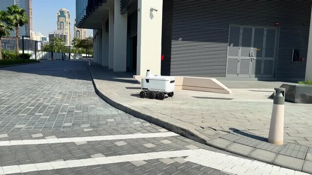 Automated Delivery Robot Service Driving on Urban Street. Modern Smart Wireless Robot Delivers Goods or Food to a Customer. New Technological Iot Business Industry of Delivery Logistic 