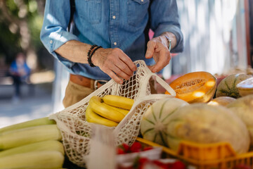 Senior man shopping at market in the city. Elderly man buying fresh vegetables and fruits from market stall.