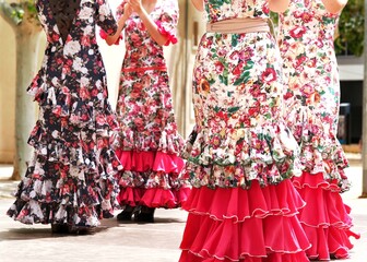 Four flamenco dancers in skirts with ruffles and frills performing Sevillanas