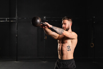 Man performing kettlebell swings, holding kettlebell in both hands. Routine workout for physical...
