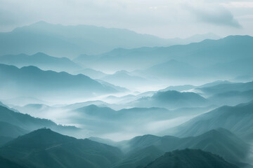 Fototapeta premium A tranquil view of the layers of mountain ridges disappearing into misty clouds, with their soft outlines and muted colors.