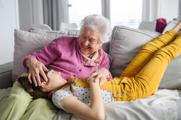 Cute girl lying head on gradmother knees. Portrait of an elderly woman spending time with...