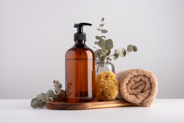 Brown transparent dispenser bottle, cotton towel, natural sea sponge and eucalyptus.