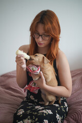 Obraz premium Young redhead woman feeding pet dog puppy with a milk bottle 