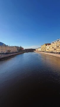 Russia, April 09, 2024: The channel in St. Petersburg in the spring. Bridges and historical buildings on the river embankment, people walking along the embankment. Reflections of houses in the water. 