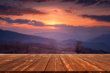 Autumn beautiful background with sunset over mountains and empty wooden table in nature outdoor....