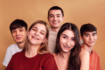 Obraz premium A group of laughing teenagers in casual clothes. The five friends are smiling. Happy girls and boys have fun together. A studio shot.