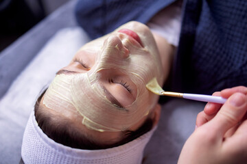 beauty master applies a rejuvenating mask to the clients face
