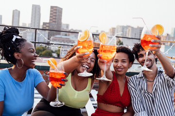 Company of four cheerful friends are enjoying tasty cocktails. Roof party