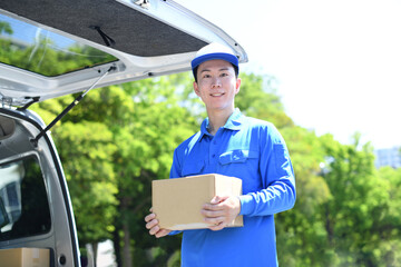屋外で荷物を運ぶ配送ドライバーの男性
