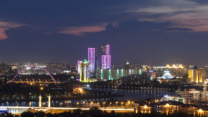 Obraz premium Elevated night view over the city center and central business district with bridge and river timelapse from rooftop, Kazakhstan, Astana