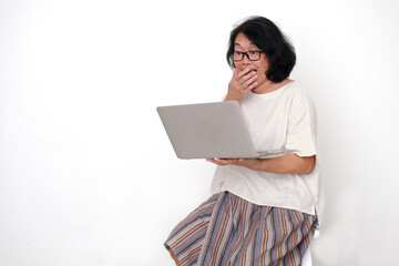 A woman is using a laptop to get connected with others; smiling, surprised, happy expression