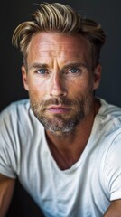 Obraz premium Handsome confident blond man, staring serious and cool at camera, wearing white t-shirt, white background