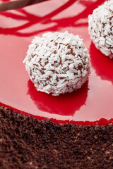 Coconut truffles on red glaze decorating handmade chocolate cake
