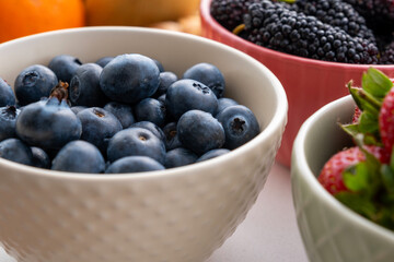 Close-up view of blueberries, black mulberries and strawberries in fruit cups next to the fruit...