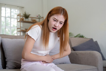 Asian woman having painful from stomach ache at home, Female suffering with abdominal pain