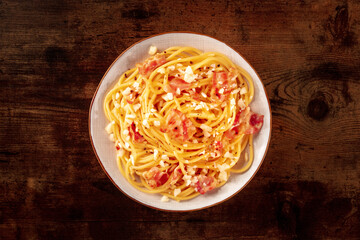 Carbonara pasta dish, traditional Italian spaghetti with pancetta and cheese, overhead flat lay shot on a rustic background
