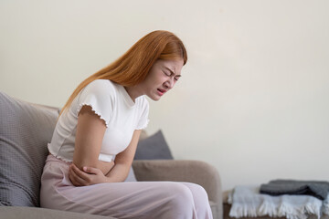 Asian woman having painful from stomach ache at home, Female suffering with abdominal pain