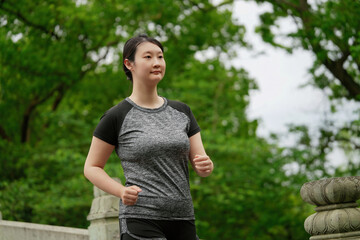 Determined Woman Jogging Through Lush Green Park