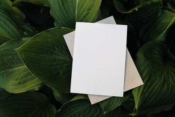 Moody summer tropical wedding stationery mock-up. Blank greeting card, envelope over dark green...