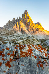 Monte Paterno mountain illuminated by a brilliant golden sun at golden hour sunset in early autumn...