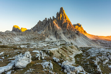 Monte Paterno mountain illuminated by a brilliant golden sun at golden hour sunset in early autumn...