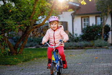Little preschool girl riding bike. Kid on bicycle outdoors. Happy child enjoying bike ride on her...