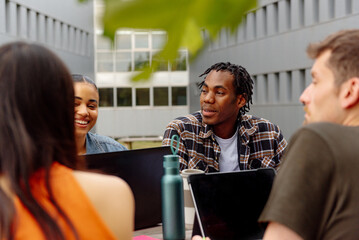 young male college student sitting with his diverse, multiracial group of classmates studying together or doing a college project