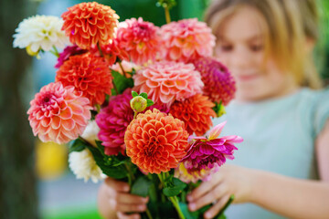 Close up of little preschool girl with dahlia flower bouquet. Close-up of happy child holding...