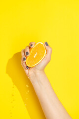 Hand holding, squeezing halved orange