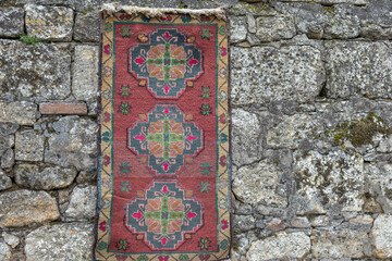 Antique oriental carpets with patterns made of natural wool. Antique carpets on a stone wall in an ancient city. Islamic multicolored carpets with patterns. The oriental carpet