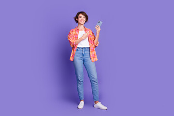 Full size photo of pretty young girl point finger smart phone wear shirt isolated on violet color background