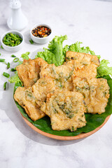 Fried Tempe or Tempe Mendoan served on a plate with spicy sambal and lettuce. Tempe Mendoan is traditional Indonesian Food made from tempeh with flour and spring onions.