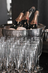 Many empty champagne glasses prepared for a gala event against on the blurred bottles background