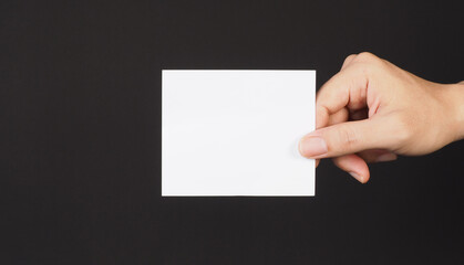 Hand holding white blank card on Black background.