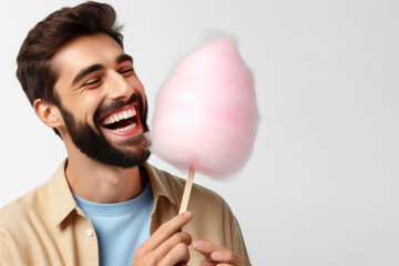 Happy man eating cotton candy on a stick on a white background