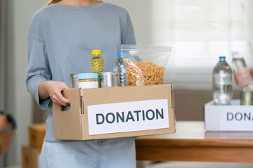 charity, donation and volunteering concept. Volunteer prepare foodstuff box containing food to donate to people poor, disaster victim at home