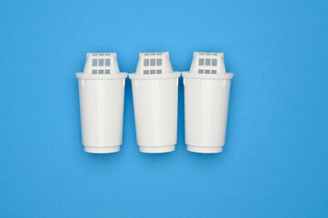 Three new filter cartridges for water purification against a blue background, top view. Water...