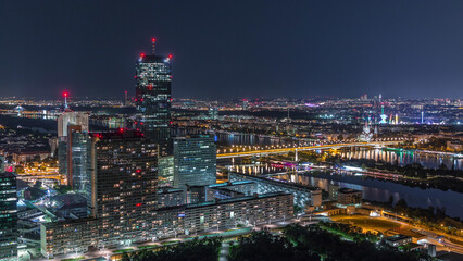 Fototapeta premium Aerial panoramic view over Vienna city with skyscrapers, historic buildings and a riverside promenade night timelapse in Austria.