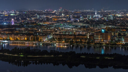 Fototapeta premium Aerial panoramic view over Vienna city with skyscrapers, historic buildings and a riverside promenade night timelapse in Austria.